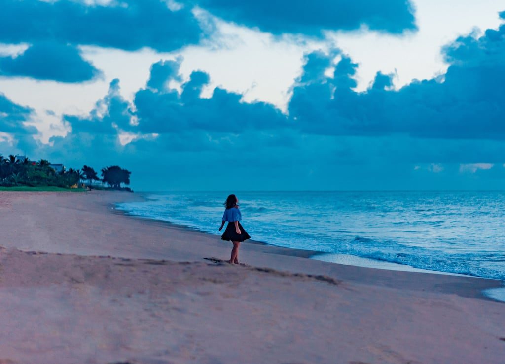 A praia de Manaíra, pouco antes do amanhecer, ainda com as luzes da cidade acesas e um tom azulado no céu. Vale a pena assistir ao nascer do sol nessa bela praia de João Pessoa! Veja mais fotos no post.